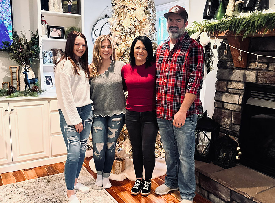 photo of Mother Cluckers owner Sabrina & family in front of Christmas tree & fireplace
